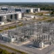 Data-center campus beside a large electrical substation and transmission lines.