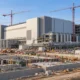 Semiconductor fabrication facility under construction with cranes and utility works.