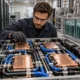 Technician inspecting server cold plates and coolant hoses in a cooling lab.