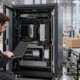 Technician inspecting an edge-computing cabinet beside a warehouse conveyor.