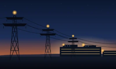 Illustration of high-voltage transmission towers at dusk carrying power lines toward a lit data-center campus.