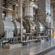 Gas turbine generator and industrial piping beside a data-center campus.