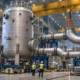 Reactor pressure vessel and pipe modules inside a manufacturing hall.