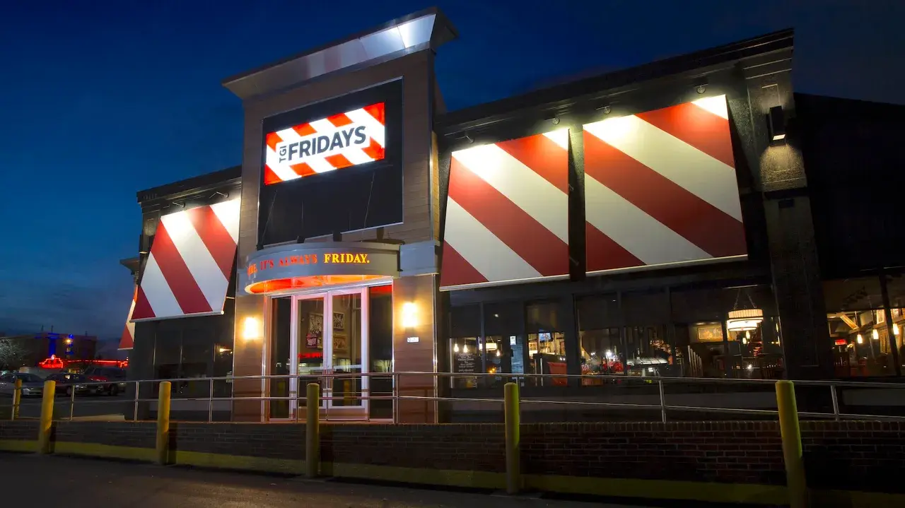 TGI Fridays restaurant exterior at night with its red-and-white striped facade