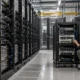 Dense server racks beside a smaller inference test rack and engineer.