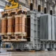 Large utility transformer and copper windings inside an electrical equipment factory.